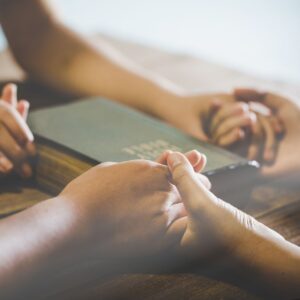 a group of people holding hands around a Bible