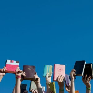 people holding Bibles in the air