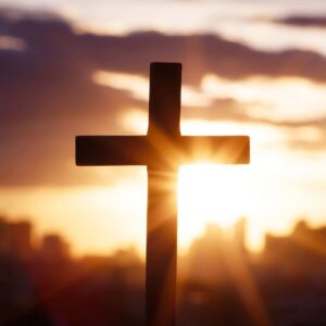 A cross backlit by a sunset