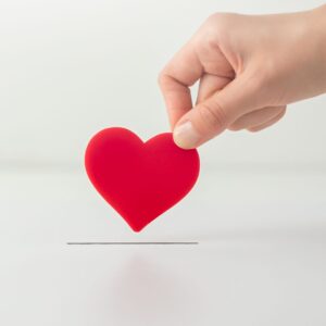 A hand placing a heart-shaped paper into a slot